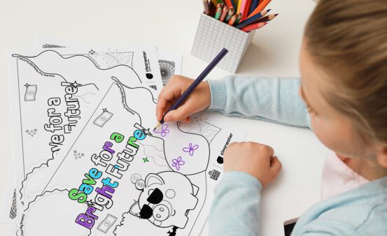 Young child drawing on a coloring sheet.